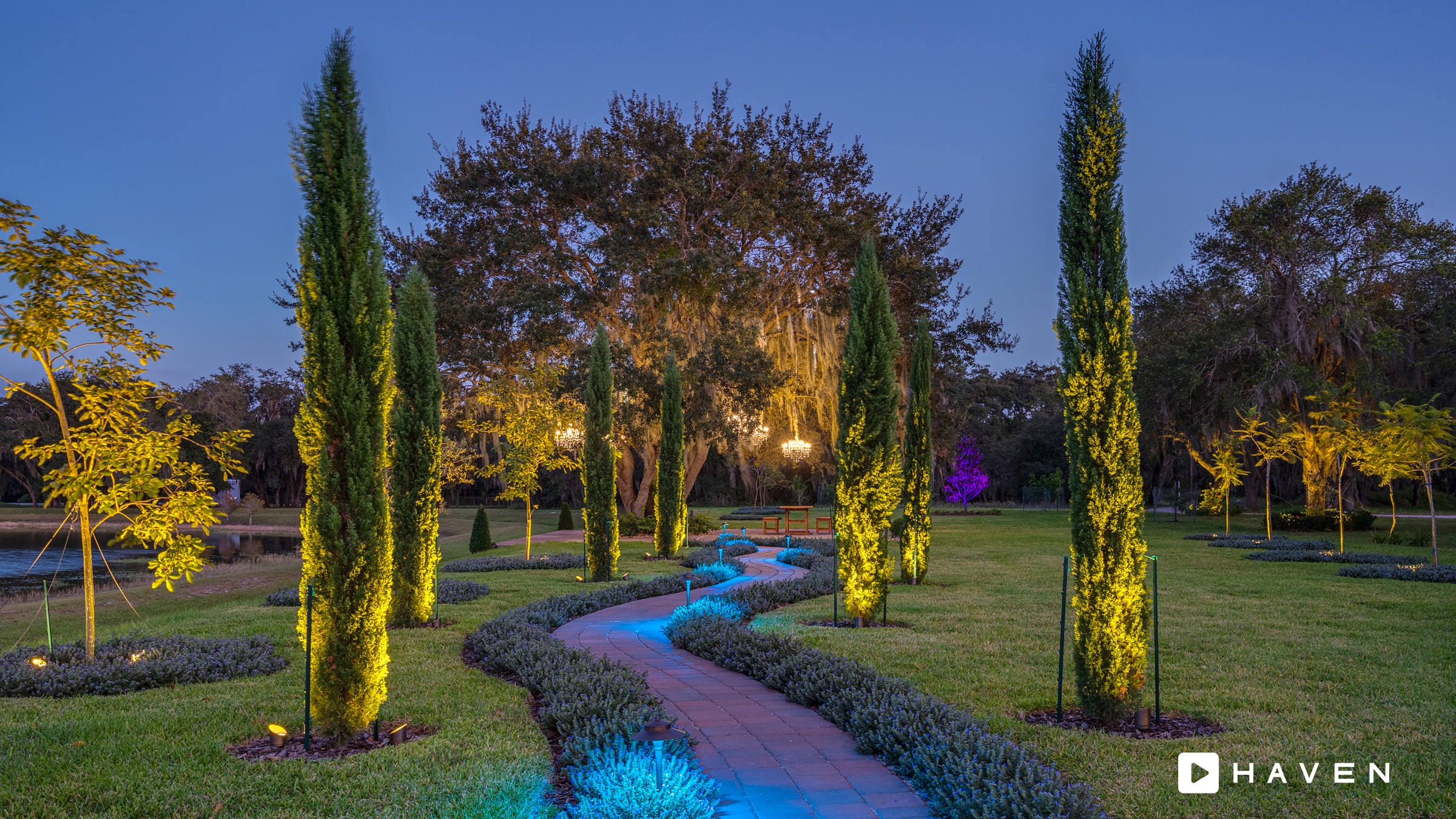 Landscape lighting along a palm-lined walkway at dusk