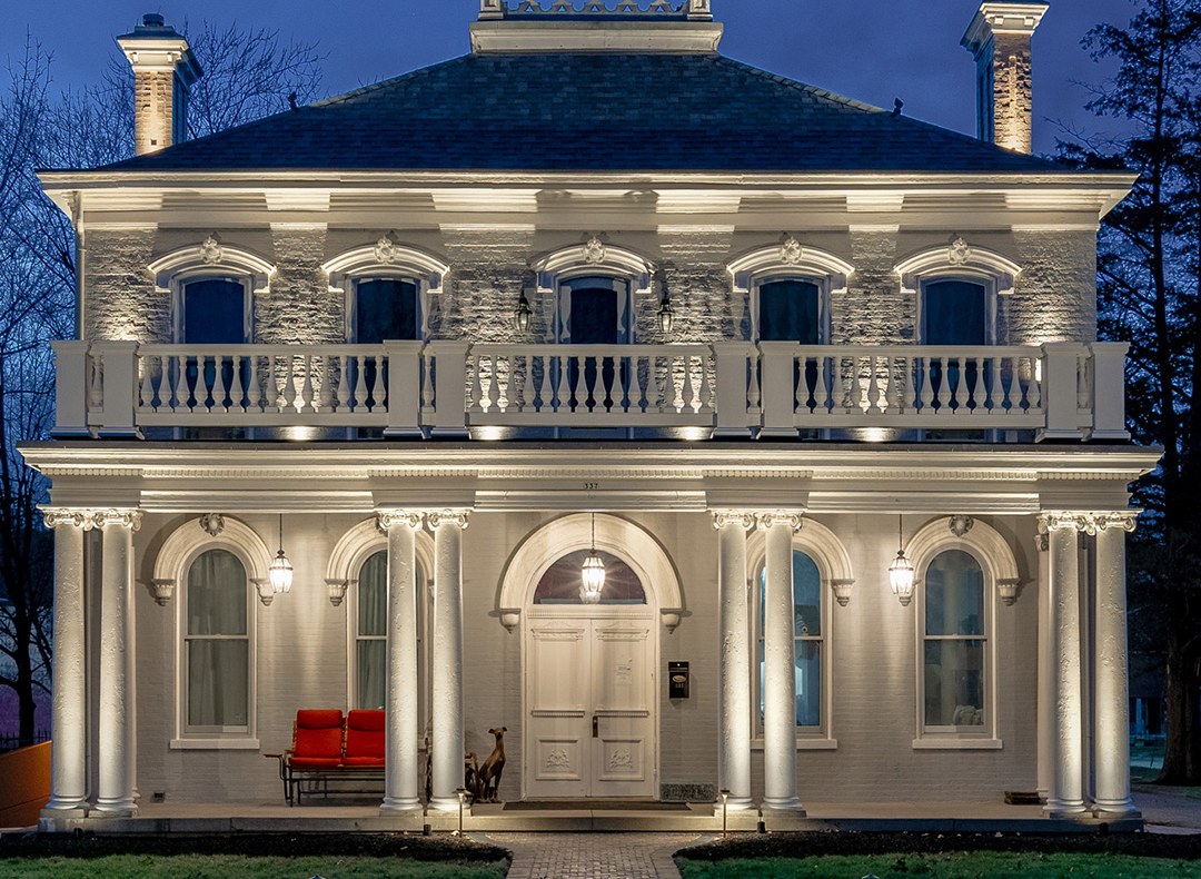 Architectural uplighting on the columns and balcony of a two-story home at night